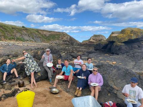 Group people enjoying a cook-up of seaweed they have foraged on the beach