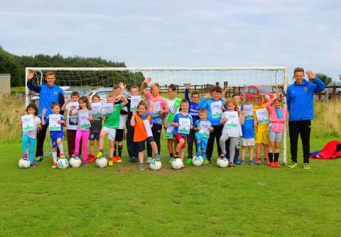 Boys and girls football team photo by goal