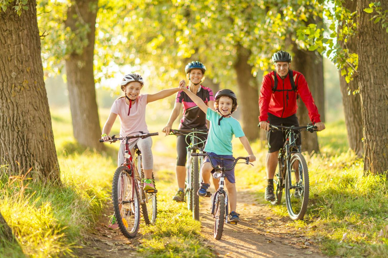 Happy family cycling through a forest in dappled sunlight